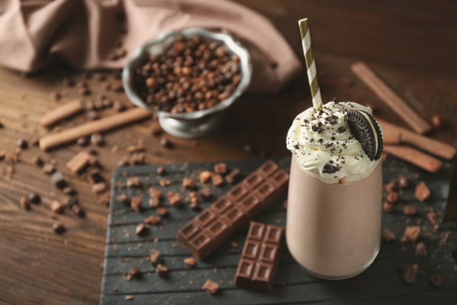 Delicious creamy milkshake with cookie on wooden background