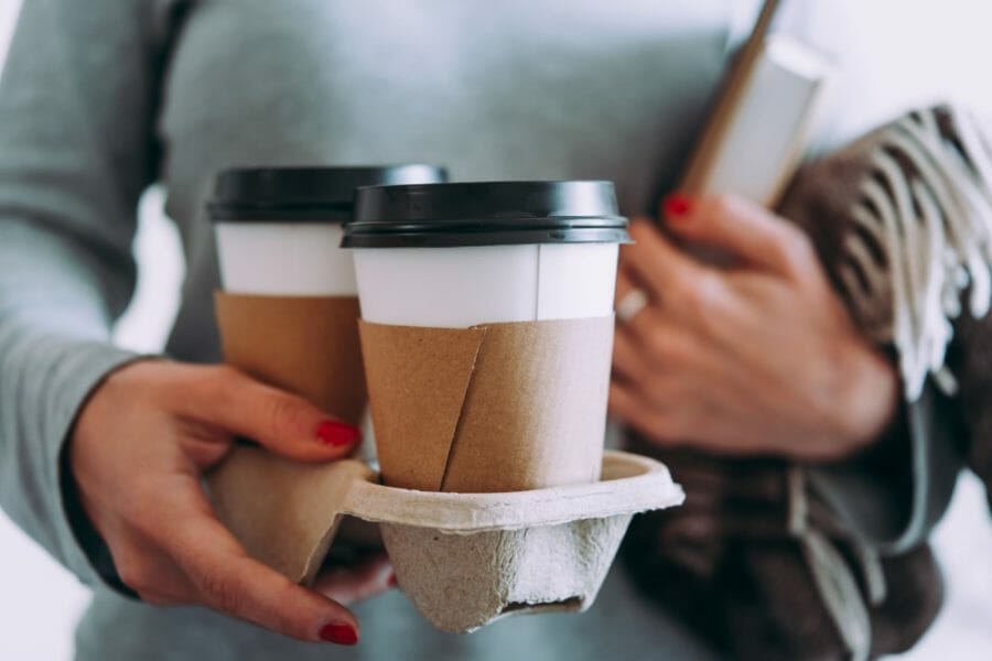 Close up of a woman holding hot coffee in a takeaway tray