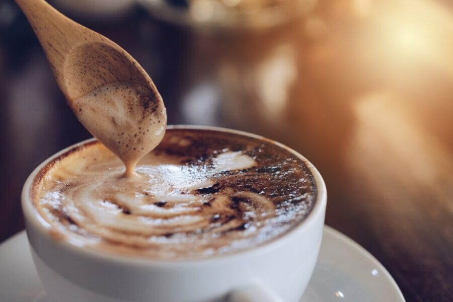 Close up of wooden spoon with a cup of hot Mocha coffee.