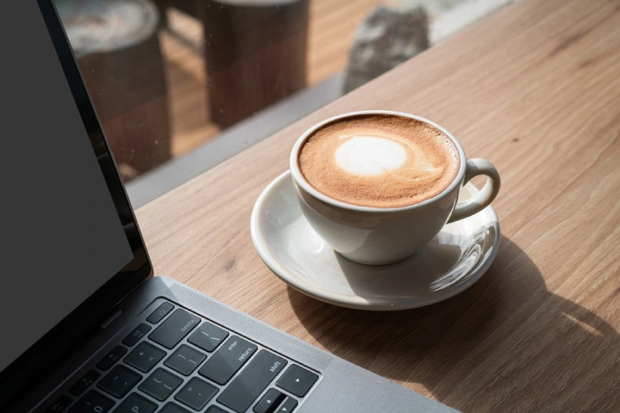 A latte sitting next to a laptop