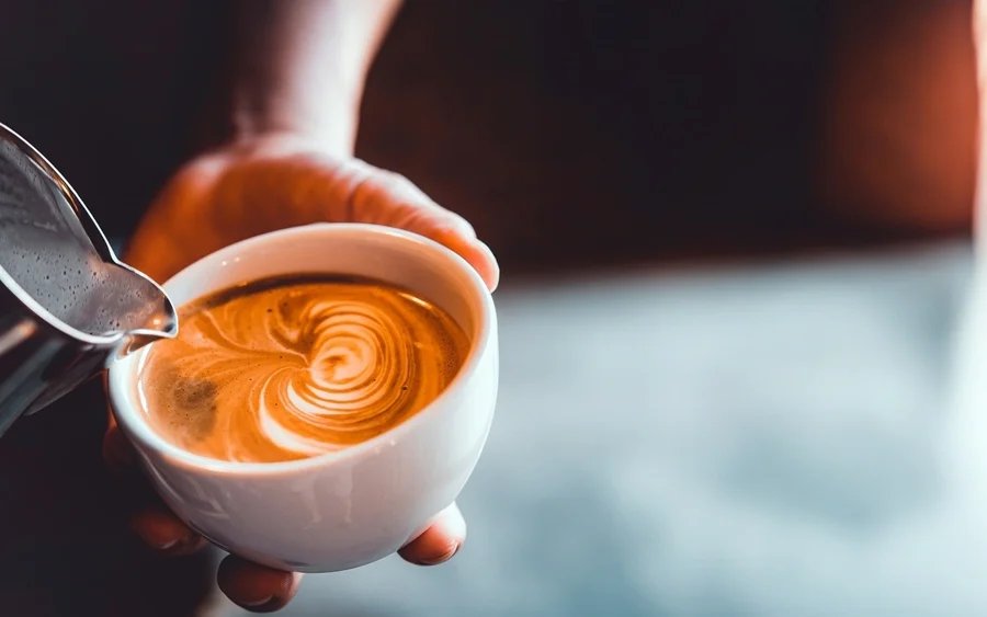 Vintage tone of barista pour milk to making latte art coffee at cafe